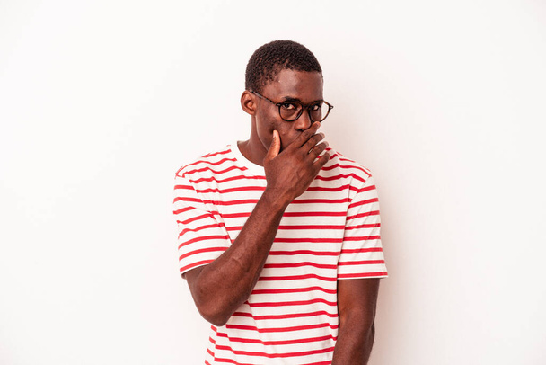 Giovane uomo afro-americano isolato su sfondo bianco che copre la bocca con le mani cercando preoccupato. - Foto, immagini