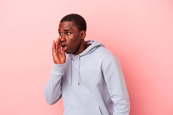 Young African American man isolated on pink background being shocked because of something she has seen. - Foto, afbeelding