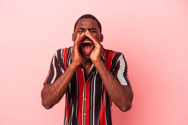 jonge afrikaanse amerikaanse man geïsoleerd op roze achtergrond schreeuwen opgewonden naar voren. - Foto, afbeelding