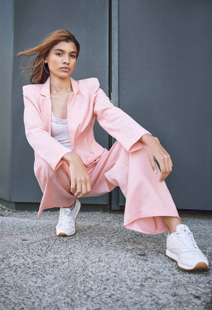 Portrait of a young trendy and confident mixed race woman looking stylish while posing and spending time in the city. Fashionable hispanic woman wearing pink clothes and enjoying time in the city. - Zdjęcie, obraz