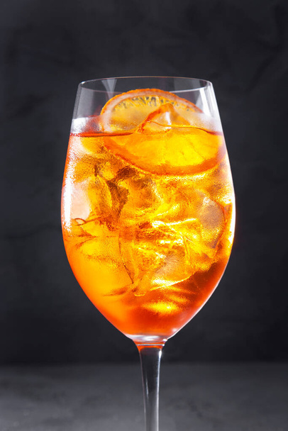 A cocktail with ice and an orange in a glass that stands on a concrete table - Foto, Bild
