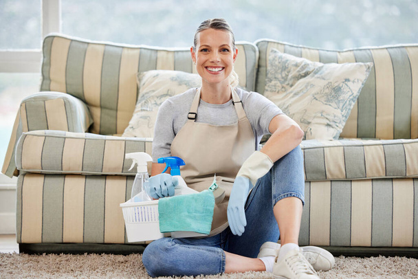 Portrait of a woman holding a basket with cleaning supplies at home. - 写真・画像