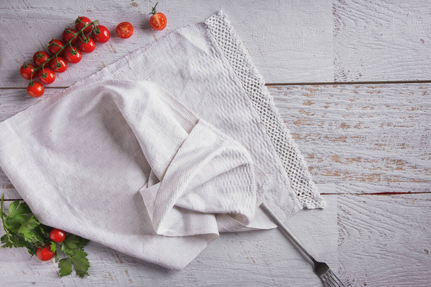 Sprigs of cherry tomatoes with towel and fork on wooden table - Fotografie, Obrázek