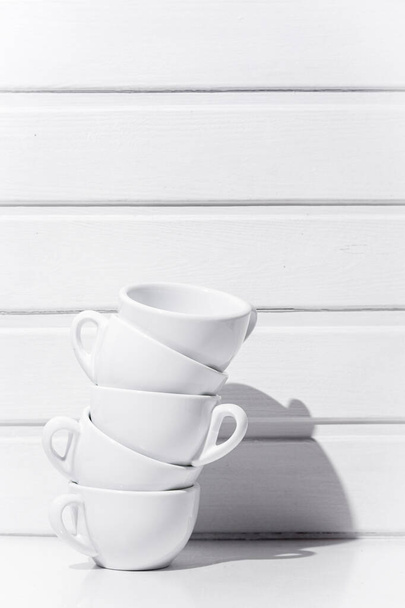 Чашки чая стоя друг на друге на белом столе и белом фоне дерева - Фото, изображение