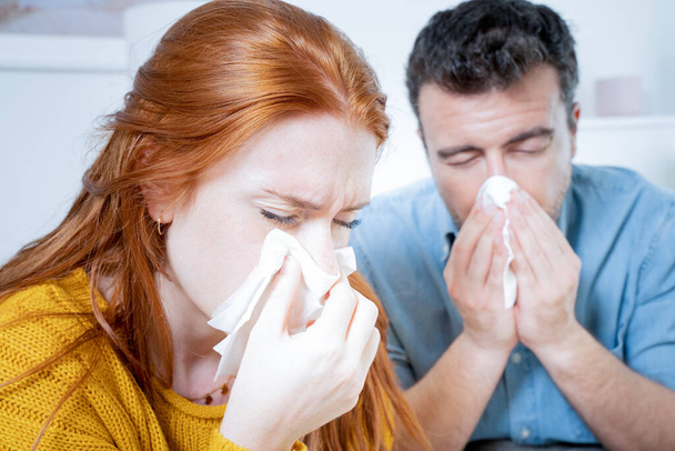Couple suffering cold and flu and sneezing nose - 写真・画像