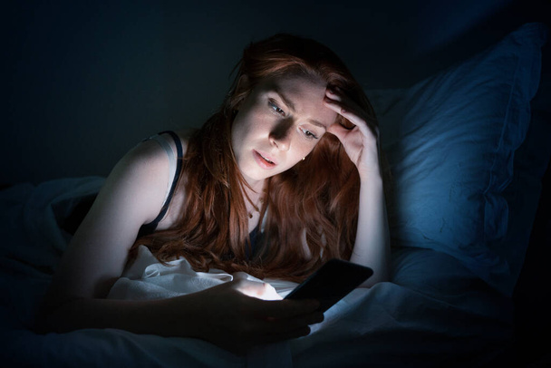 Kobieta korzystająca ze smartfona w łóżku późno w nocy w łóżku - Zdjęcie, obraz