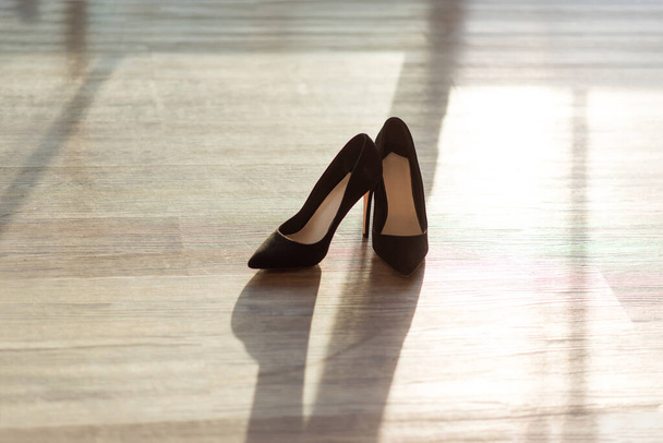 Black women's pumps with stiletto heels on a wooden floor. women's shoes - 写真・画像