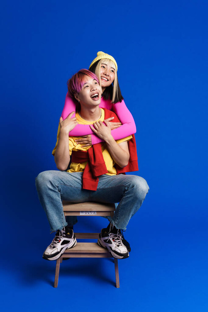 Asian couple with multicolored hair making fun together isolated over blue wall - Фото, зображення