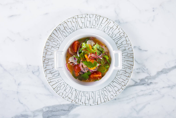 Zupa z rybą, cebulą, pietruszką, kumkwatem, pomidorami i sałatką w talerzu na marmurowym stole - Zdjęcie, obraz