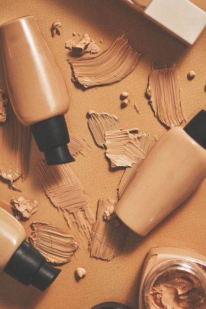 Bottles of makeup foundation and samples on beige background. Flat lay, top view - Foto, Bild