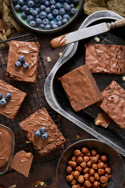 Composition of fresh homemade chocolate brownie squares melting chocolate and fresh blueberries. Close up view. Top view food. Flat layout. - Φωτογραφία, εικόνα