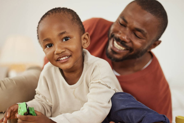 Entzückender kleiner afrikanisch-amerikanischer Junge, der mit seinem Spielzeug spielt, während er Zeit mit seinem Vater zu Hause verbringt. Niedlich schwarz Kleinkind Spaß mit Papa. - Foto, Bild
