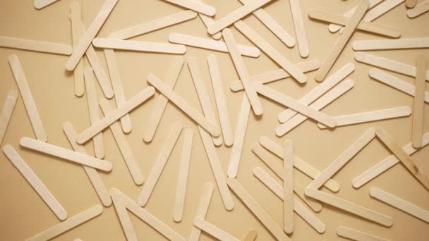 Wooden popsicle sticks, scattered on top of a beige background. Flat lay - Metraje, vídeo