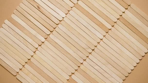 Wooden popsicle sticks, placed in a rows on top of a beige background. Flat lay - Metraje, vídeo