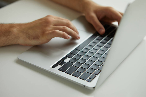 чоловік працює на ноутбуці, його руки крупним планом
 - Фото, зображення