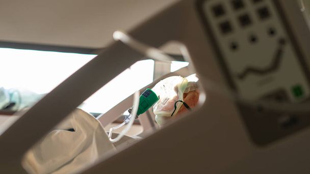person in a hospital bed with a breathing oxygen mask - Foto, Imagen