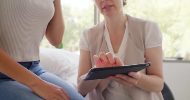 Closeup of a physical therapist using a digital tablet to show patient scan results. Massage expert talking to a female client in an office. A woman getting medical advice from a doctor about pain. - Materiaali, video