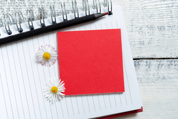 Haftnotiz mit neuen Ideen über Notizbuch mit Bleistift und Blumen. - Foto, Bild