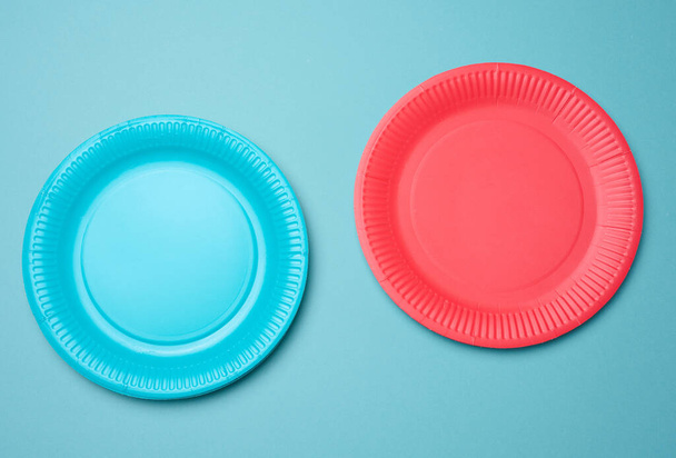 Empty blue, red paper disposable plates on a blue background, top view. The concept of rejection of plastic, environmental conservation - Photo, Image
