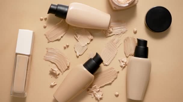 Botellas de maquillaje base y muestras sobre fondo beige. Piso tendido, vista superior - Metraje, vídeo