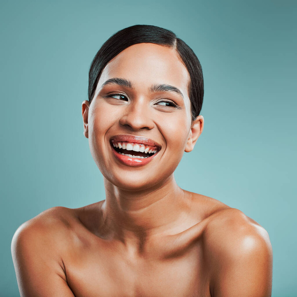 A young beautiful mixed race woman with smooth soft skin posing and smiling against a green studio background. Attractive Hispanic female with stylish makeup posing in studio. - Foto, afbeelding