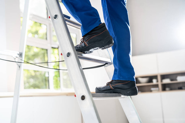 Low Section View Of A Handyman's Foot Climbing Ladder - Foto, immagini