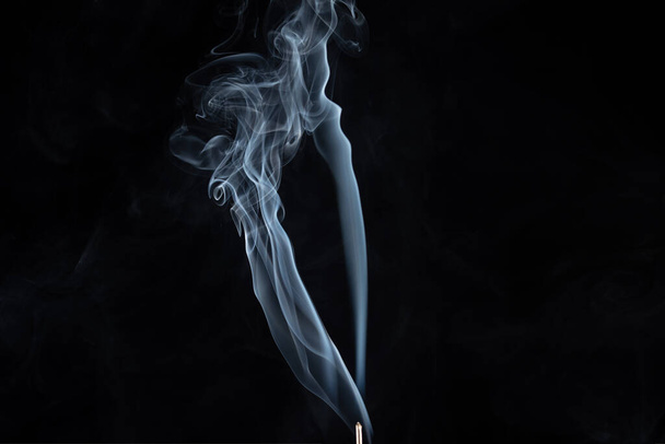 Wierook stokje met rook tegen zwarte achtergrond - Foto, afbeelding
