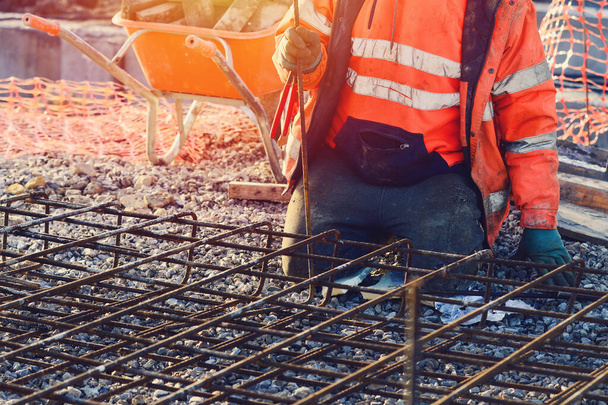 İnşaatçının elleri inşaat alanındaki çelik takviye çubuklarını tamir ediyor. Çelik tamiri destek kafesi. Seçici odak - Fotoğraf, Görsel