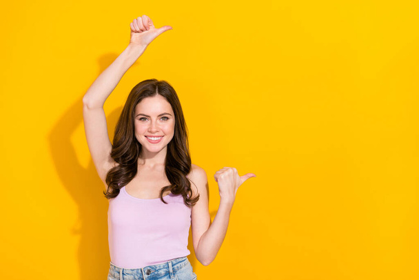 Photo of positive gorgeous girl indicate thumbs empty space promotion isolated on yellow color background. - Foto, Imagem