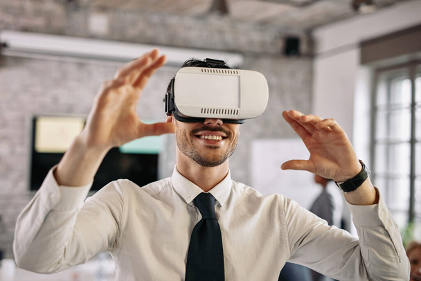 Молодий бізнесмен розважається на роботі, одягаючи симулятор віртуальної реальності
. - Фото, зображення