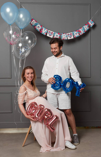 Full length image of a young excited woman and man holding balloon during gender reveal party. - Fotografie, Obrázek