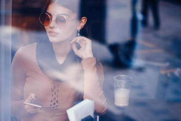 brunette girl using her cell phone while sitting at a rastaurant for lunch - Foto, Imagem