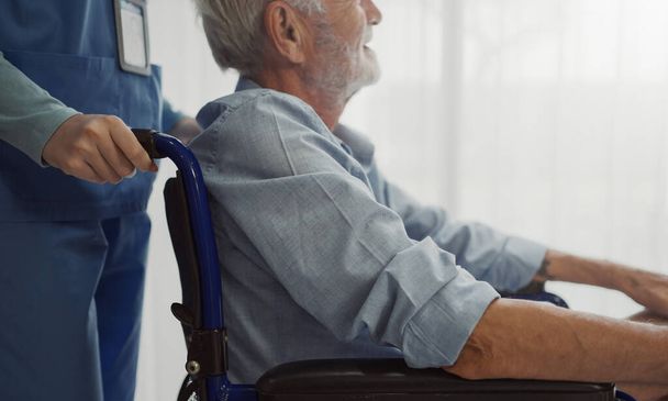 Verpleegster zet rolstoel met seniorraam. Ongelukkige oudere man met een geriatrische of depressie ziekte. Therapeut die zorg draagt, ondersteuning en empathie geeft. - Foto, afbeelding