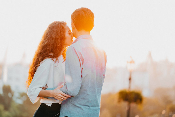 Young couple spending intimate time together in city. Sunset light, sun flares. Lovers enjoying on date. Woman and man holding hands. Love, family, care concept. High quality photo - Foto, immagini