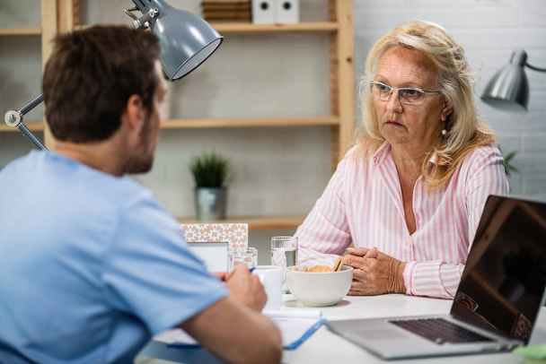Serious mature woman talking with doctor after medical exam at doctor's office.  - Photo, image