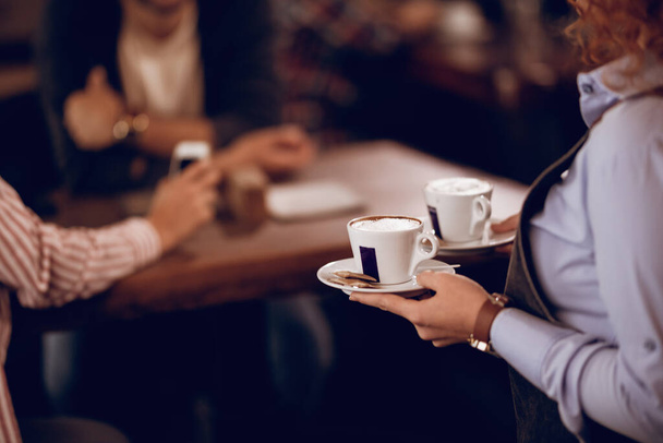 Крупный план неузнаваемой официантки, подающей кофе в кофейне. - Фото, изображение