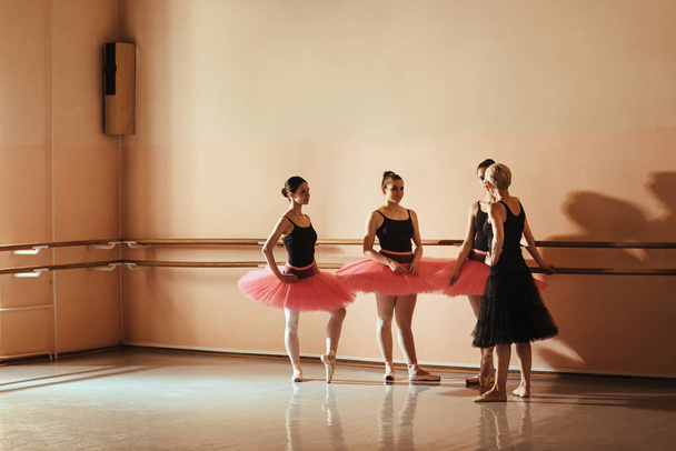 Group of female ballet dancers communicating with ballet instructor during a class at dance studio. Copy space.  - Photo, Image