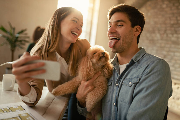 Playful freelance workers taking selfie with a poodle and having fun in the office.  - Foto, imagen