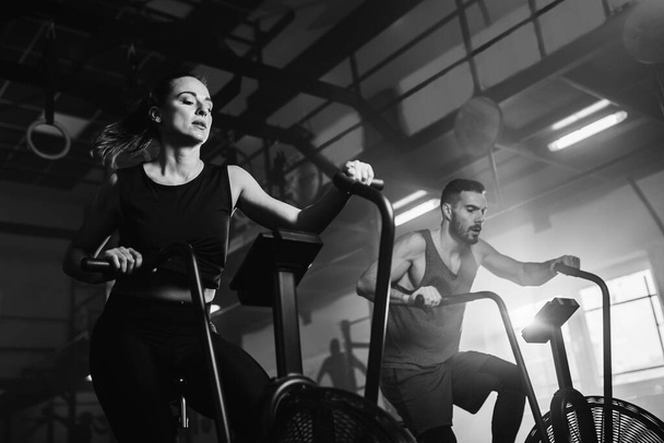 Low angle view of young athletes having sports training on exercise bikes in health club.  - Foto, afbeelding