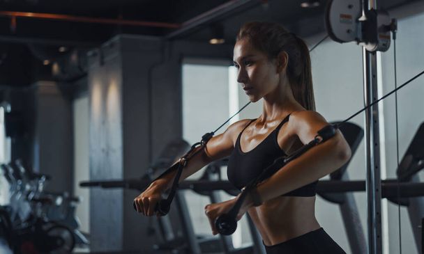 Mujer deportiva haciendo ejercicio en la estación múltiple en el gimnasio para los músculos del brazo y los hombros. Ejercicio de fitness en gimnasio. - Foto, imagen