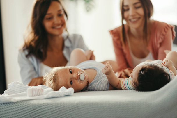 Happy mothers enjoying with their babies at home. Baby boy turning towards camera.  - Fotoğraf, Görsel