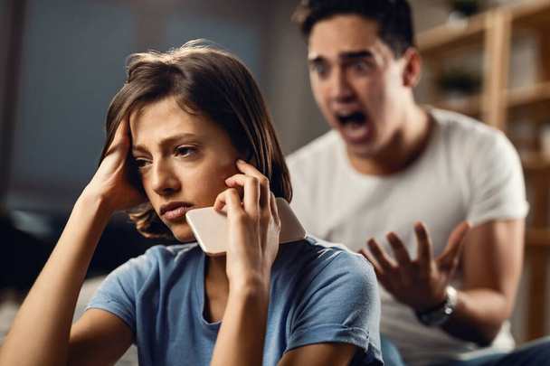 Sad woman thinking of something and ignoring her angry boyfriend who is yelling at her.  - Foto, Bild