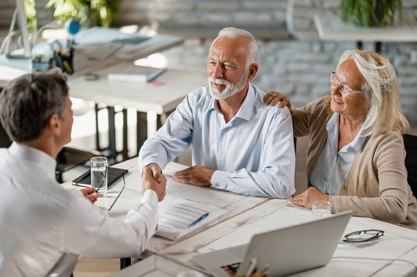 Happy senior couple shaking hands with insurance agent after successful agreement on a meeting in the office.  - Photo, Image