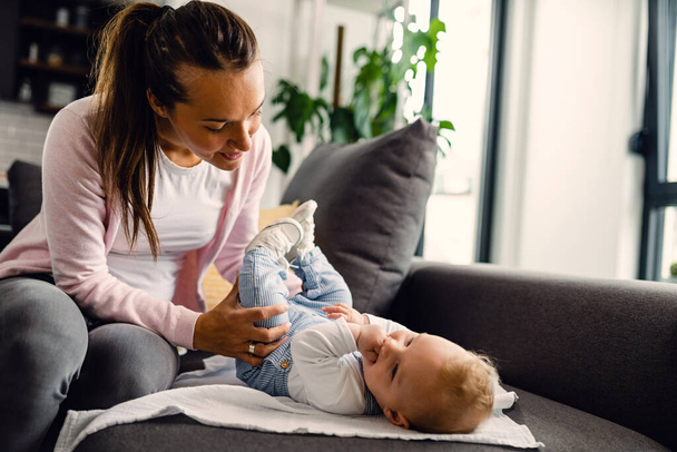 Young mother enjoying in time with her baby boy while doing infant development exercises at home.  - Foto, immagini