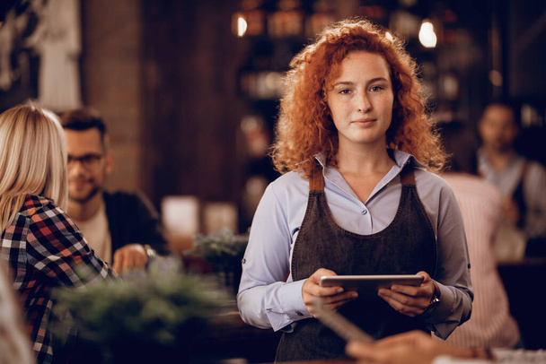 Portrait of female student with digital tablet working part-time as a waitress in a pub.  - Foto, Imagem