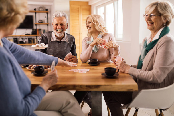 Group of happy mature people laughing while enjoying in card game at the table.  - Photo, Image
