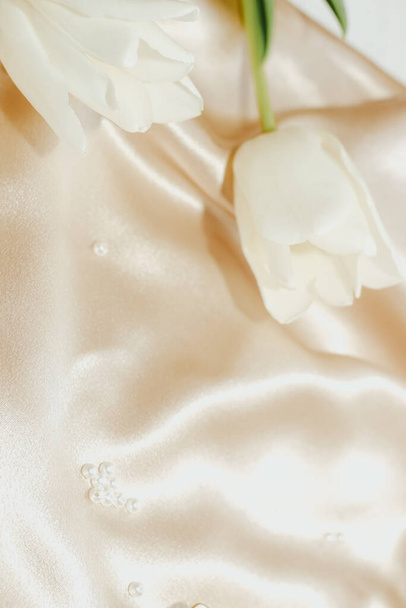 Bouquet of white tulips on silk golden nude satin background. - Фото, зображення
