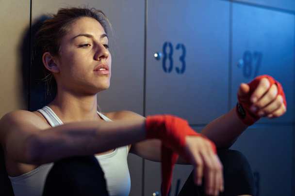 Female athlete sitting in locker room after sports training and feeling tired.  - Photo, image