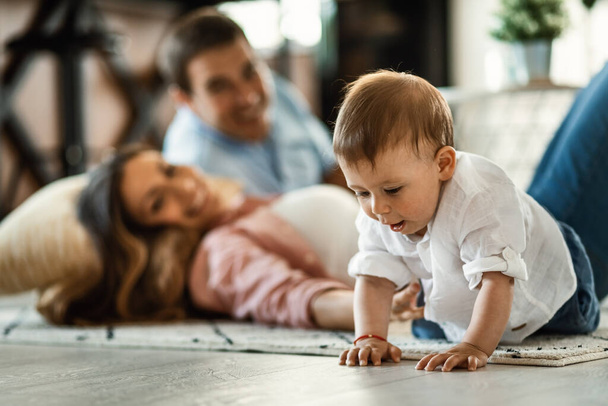 Cute baby boy spending time with his parents and crawling on the floor at home.  - Foto, Bild