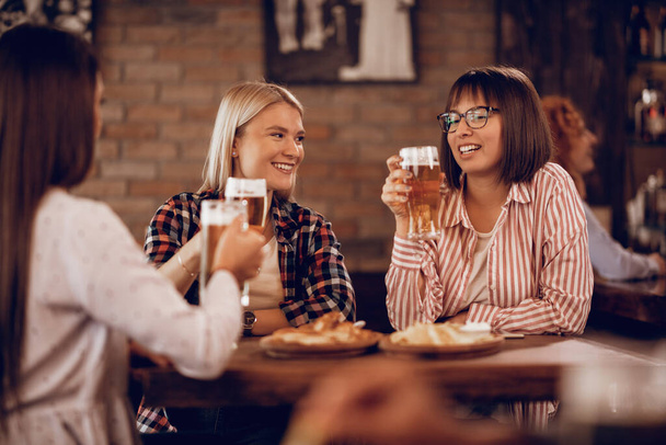Счастливые подруги общаются, когда пьют пиво в баре.  - Фото, изображение
